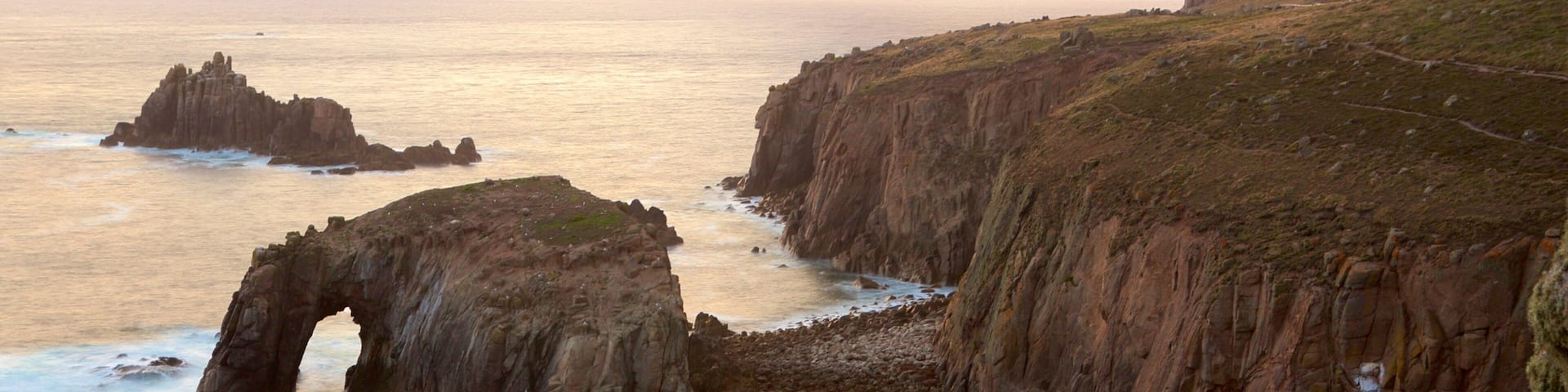 Land\'s End featuring a sunset, rocky coastline and general coastal views