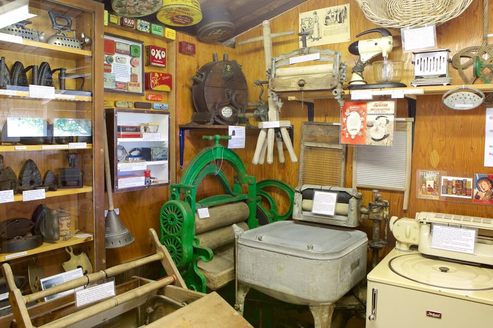A vintage shop with antique items like a green printing press, old irons, and a yellow washing machine.