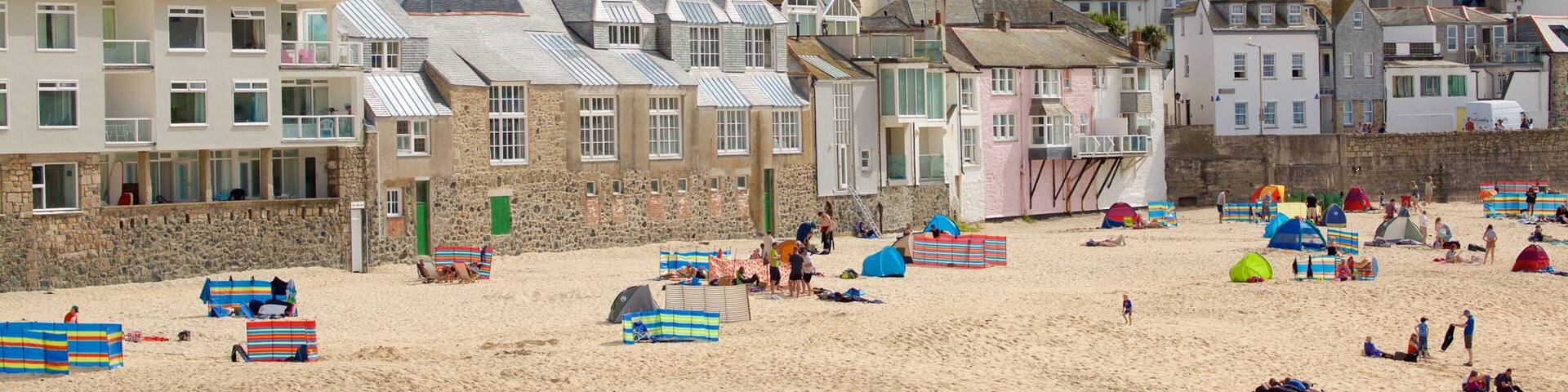 Porthmeor Beach featuring a coastal town and a sandy beach as well as a large group of people