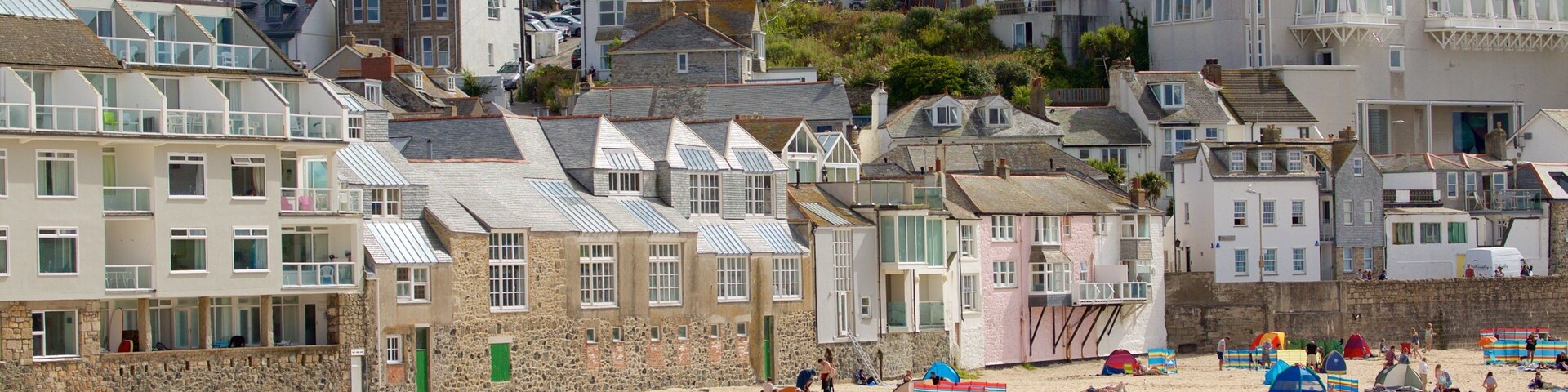 Porthmeor Beach featuring a coastal town and a sandy beach as well as a large group of people