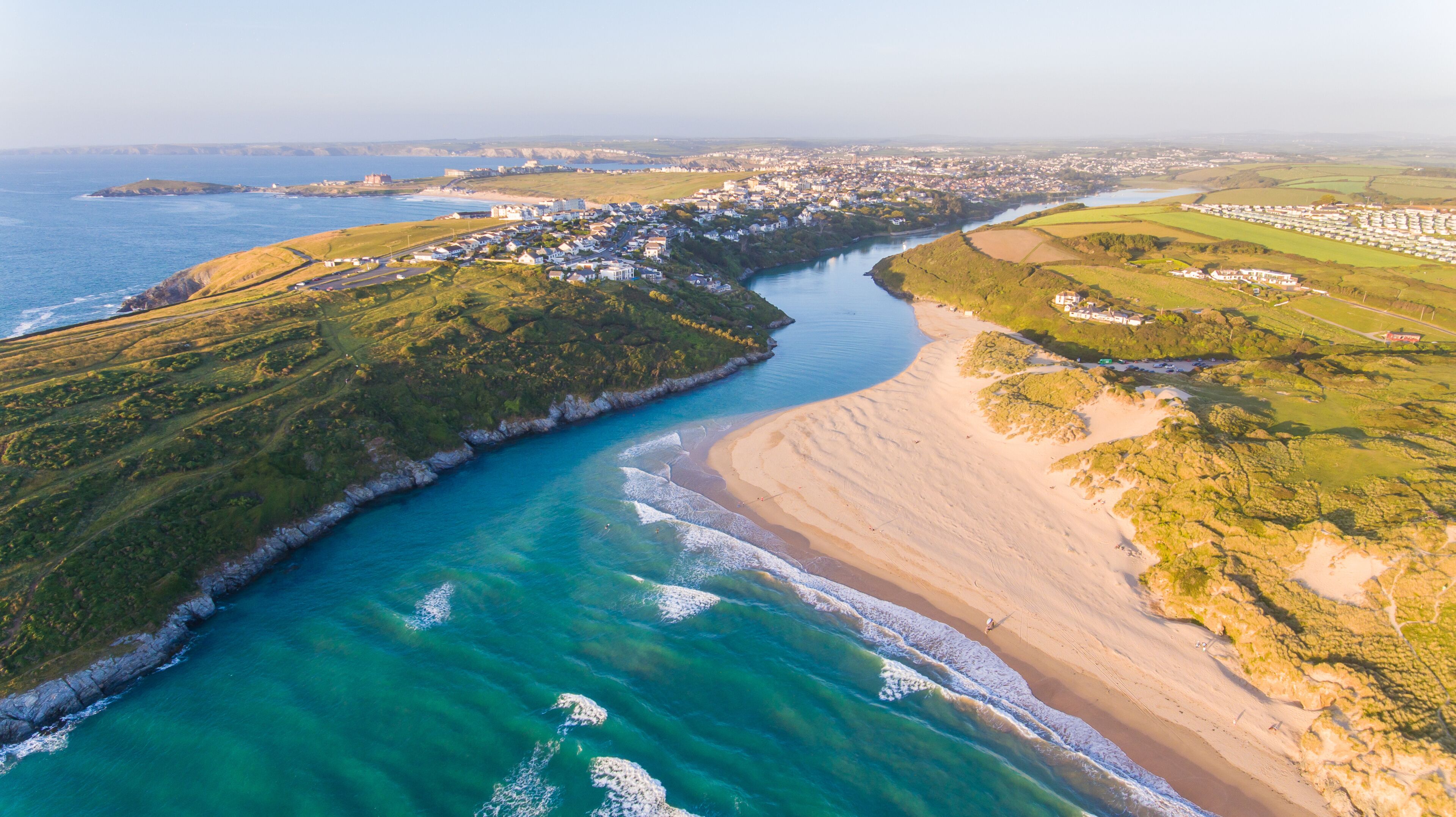 A coastal town with a river, beach, and surrounding greenery.