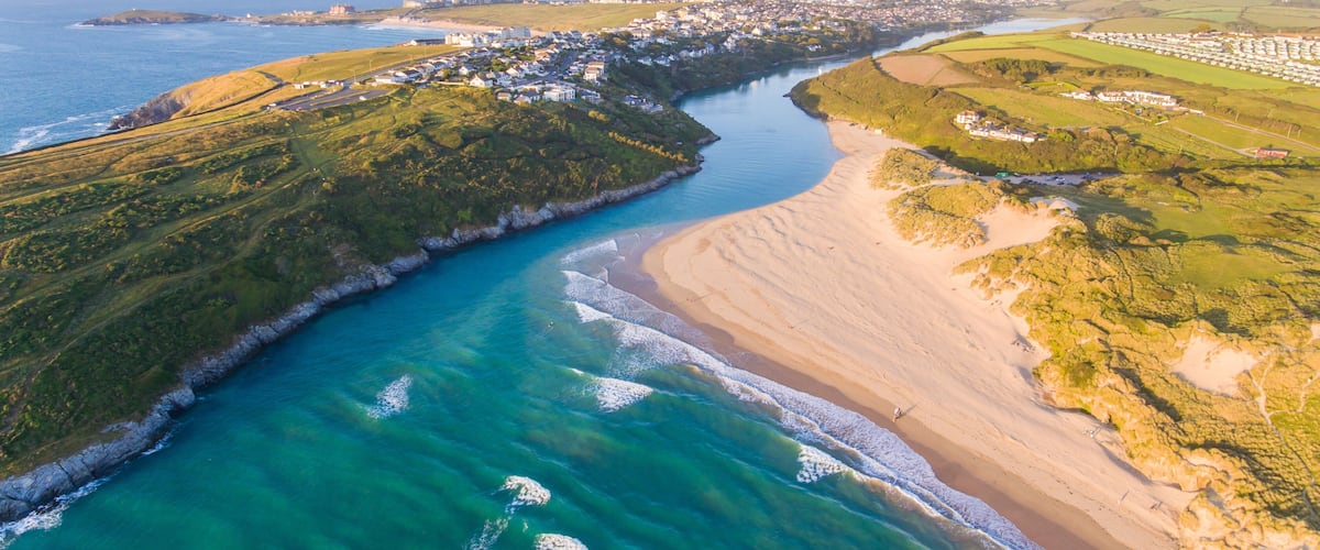 A coastal town with a river, beach, and surrounding greenery.