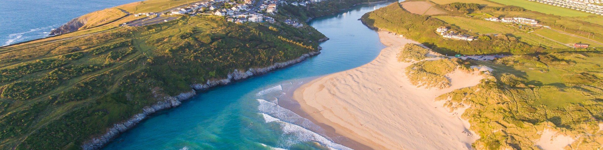 A coastal town with a river, beach, and surrounding greenery.