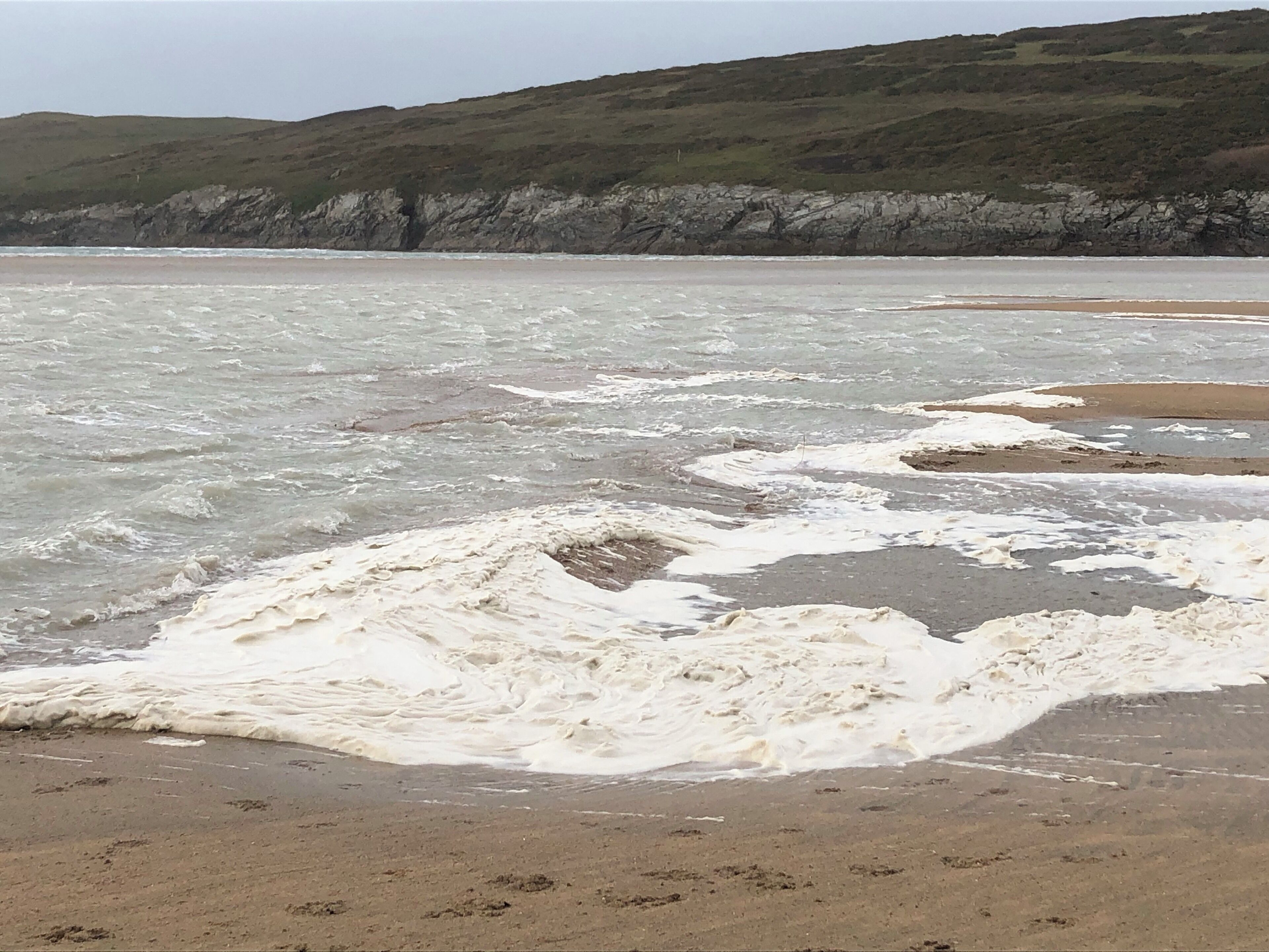 The foam on waves as the sand from a sand storm mixes with the incoming tide.