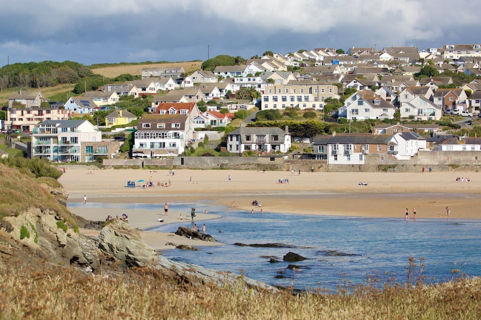 Uma cidade costeira com praia de areia, litoral rochoso e edifícios residenciais.