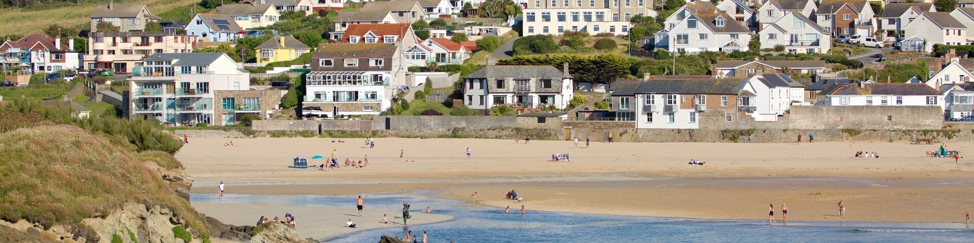A coastal town with a sandy beach, rocky shoreline, and residential buildings.