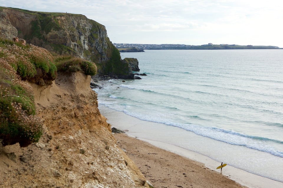 Un paisaje costero con acantilados, una playa de arena y un mar tranquilo.
