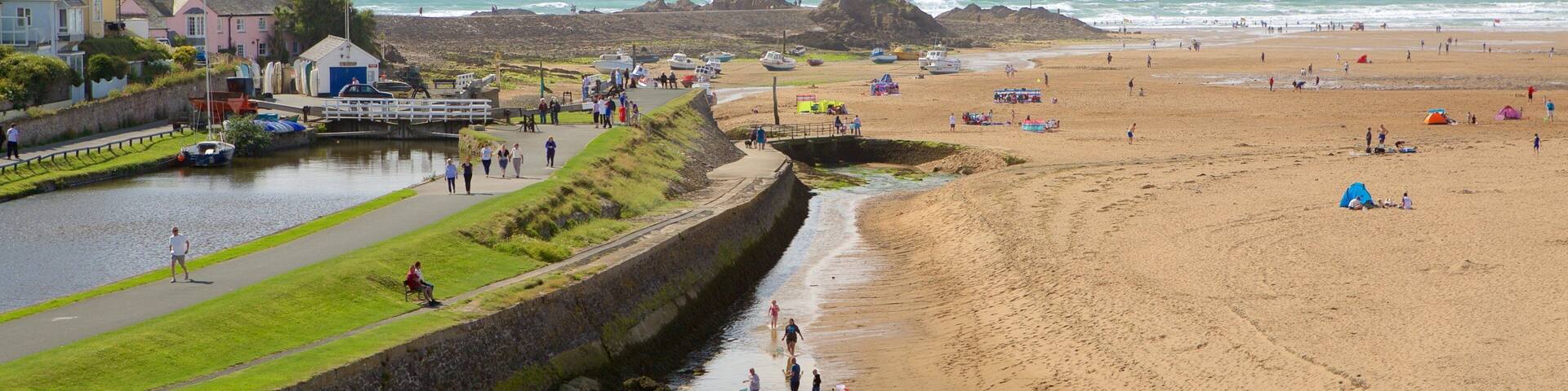 Un pueblo costero con una playa de arena, un canal y casas a lo largo de la orilla.