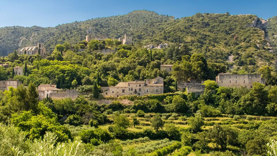 A village nestled in a valley surrounded by lush green hills and ancient stone buildings.