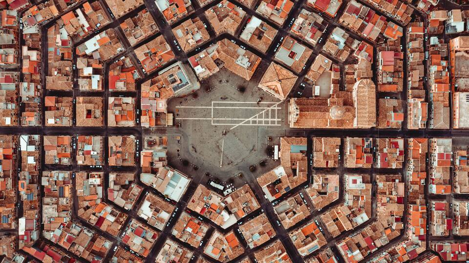 An aerial view of a city with a central open square surrounded by a grid of buildings.