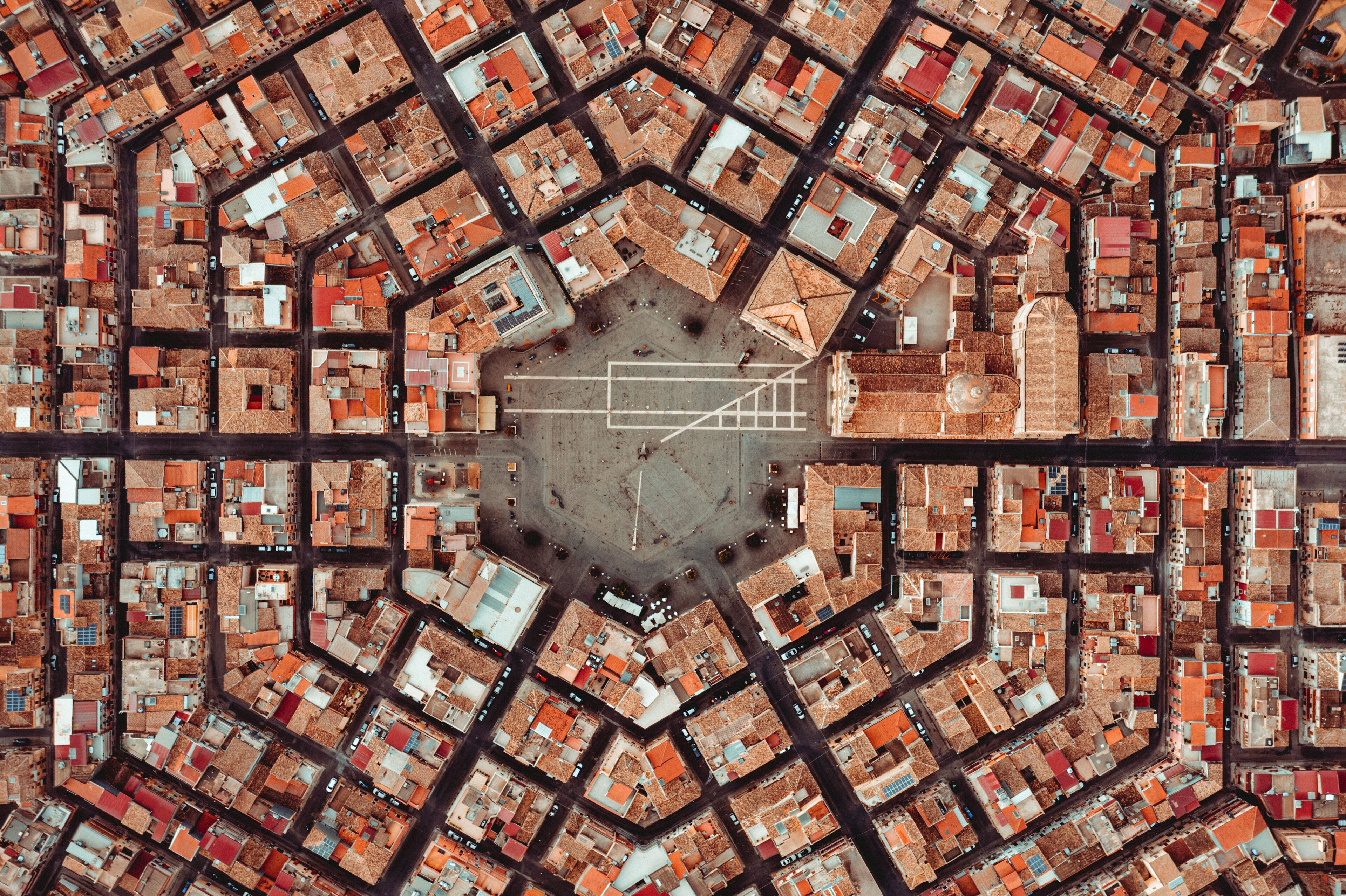 An aerial view of a city with a central open square surrounded by a grid of buildings.