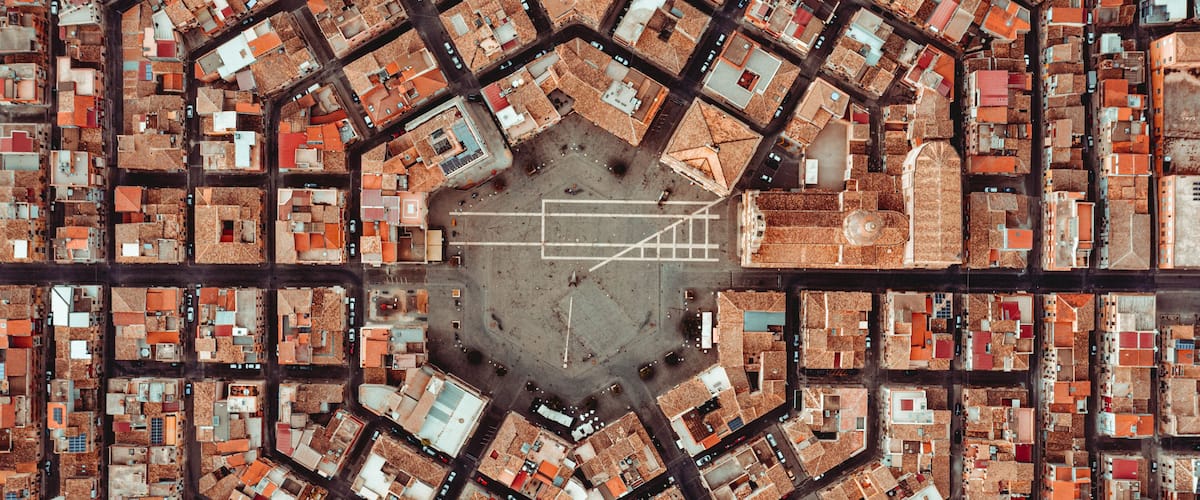 An aerial view of a city with a central open square surrounded by a grid of buildings.