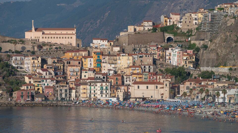 A coastal town with colorful buildings, a beach, and a large building with a tower.