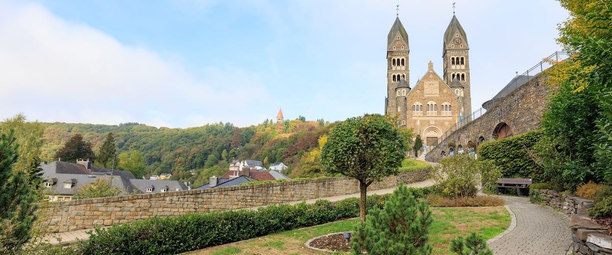 A historic church with twin towers, surrounded by a stone wall and a pathway.