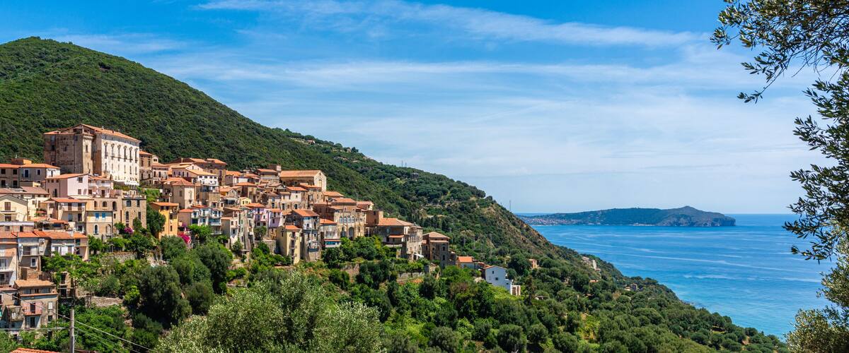 A coastal village with terracotta-roofed buildings nestled on a hillside overlooking the sea.