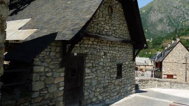 A stone building with a sloped roof, a wooden door, and a stone wall.