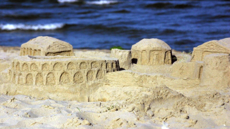 Sandcastles on a beach with the ocean in the background.
