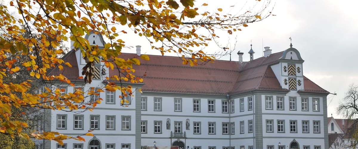 A large, white building with a red roof and multiple windows.