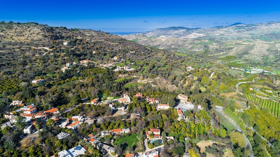 Aerial bird eye view of Miliou village hills and Akamas sea at Latchi, Paphos Cyprus. View of traditional ceramic tile roof houses near Ayii Anargyri monastery nature hotel spa from above.