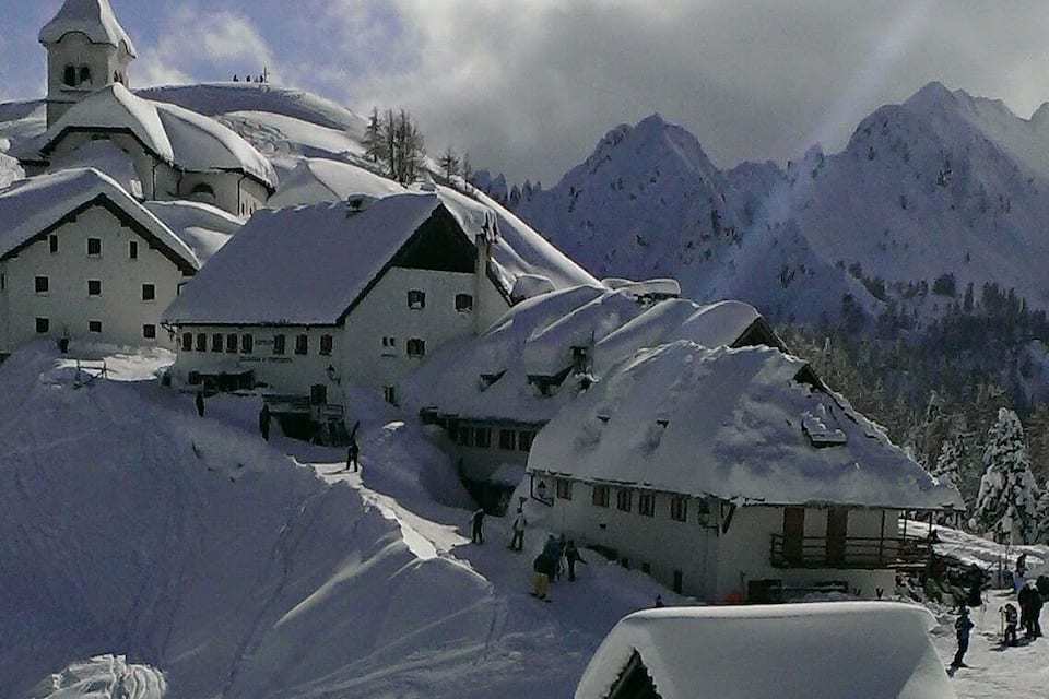 A snow-covered mountain village with traditional buildings and a church.