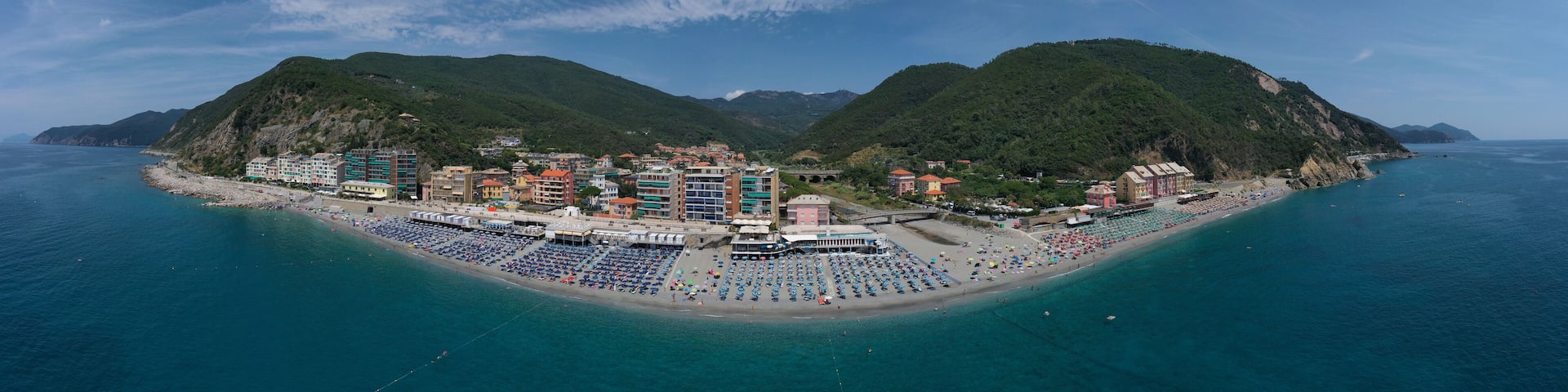 A coastal town with a beach, buildings, and mountains.
