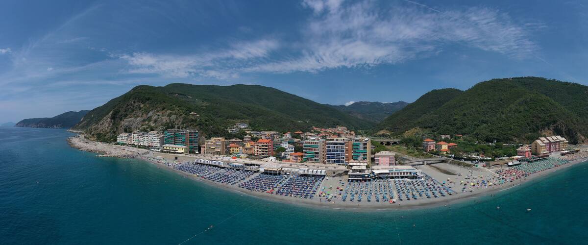 A coastal town with a beach, buildings, and mountains.