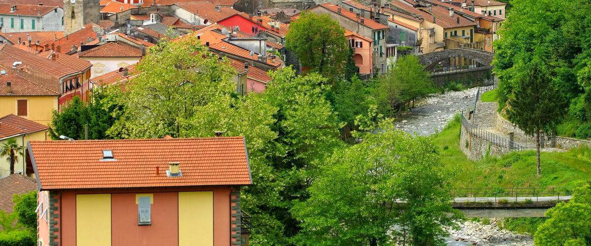 A town with historic buildings, a river, and lush green hills.
