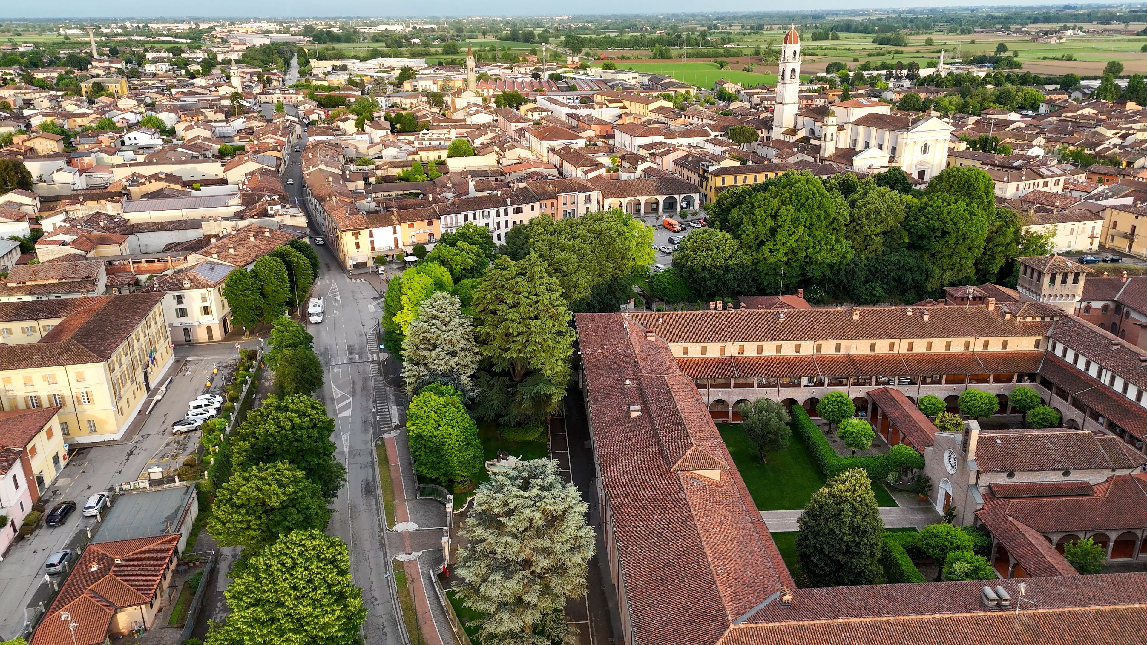 Aerial panorama revealing medieval Rocca Viscontea fortress perched above Oglio river, nestled within Pontevico town landscape, Brescia province, northern Italy