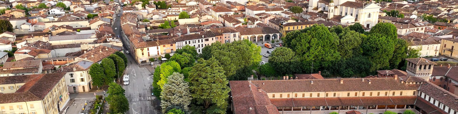Aerial panorama revealing medieval Rocca Viscontea fortress perched above Oglio river, nestled within Pontevico town landscape, Brescia province, northern Italy