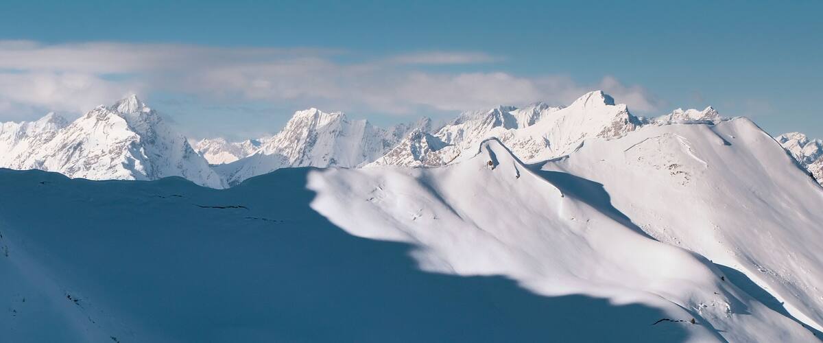 A snow-covered mountain range with sharp peaks and deep valleys.