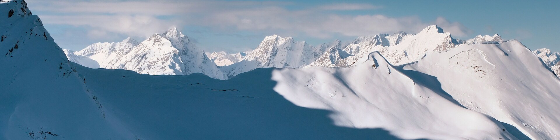 A snow-covered mountain range with sharp peaks and deep valleys.