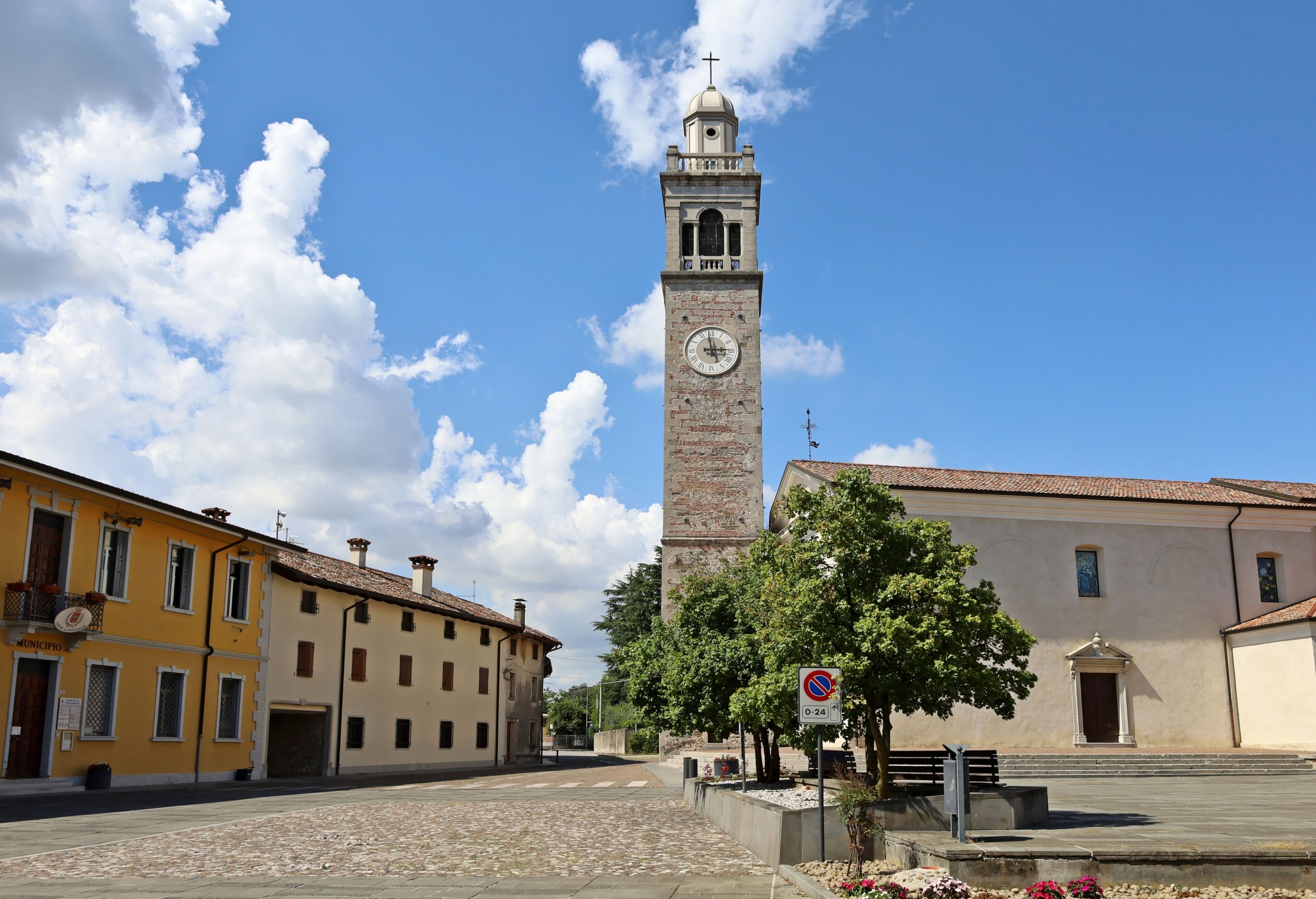 A historic clock tower, a cobblestone street, and traditional buildings.