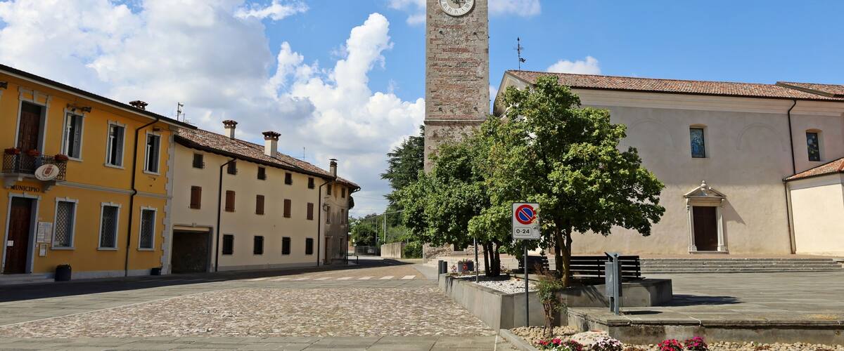 A historic clock tower, a cobblestone street, and traditional buildings.
