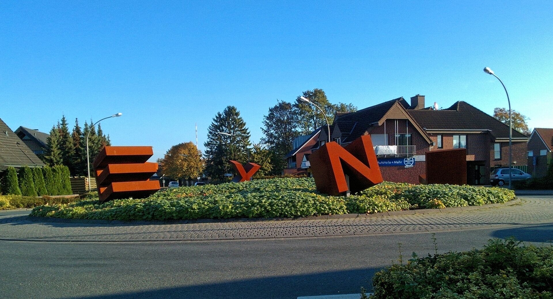 Kunst im Kreisverkehr Kiesbergstr. Ecke Frerener Str. Ecke Josefstraße, Lingen-Laxten. Die 1.60 m hohen, stählernen Buchstaben, L-A-X-T-E-N, lassen sich nur lesen, wenn man einmal ganz im Kreis herum fährt. Die Idee für die Gestaltung des ältesten Kreisverkehrs in Lingen entstand 2012 in Zusammenarbeit zwischen Ortsrat und Verwaltung. 2015 wurde das Kunstwerk realisiert.