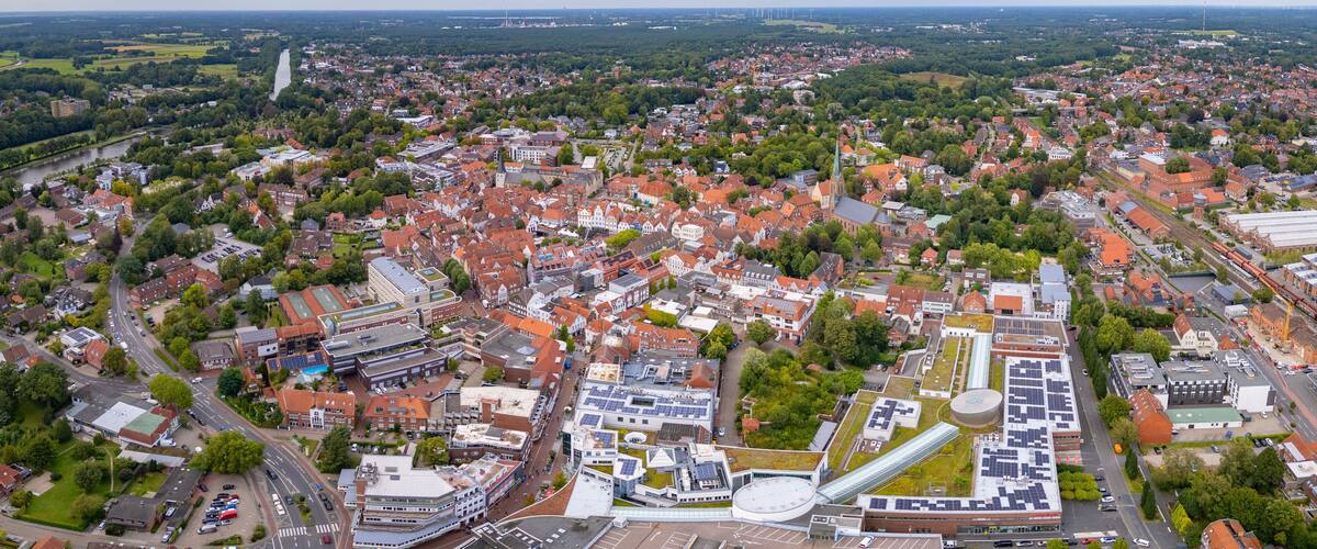 An aerial view of a city with a river, green spaces, and modern buildings.