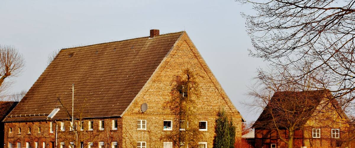 A large, triangular-roofed brick building with multiple windows and a satellite dish.