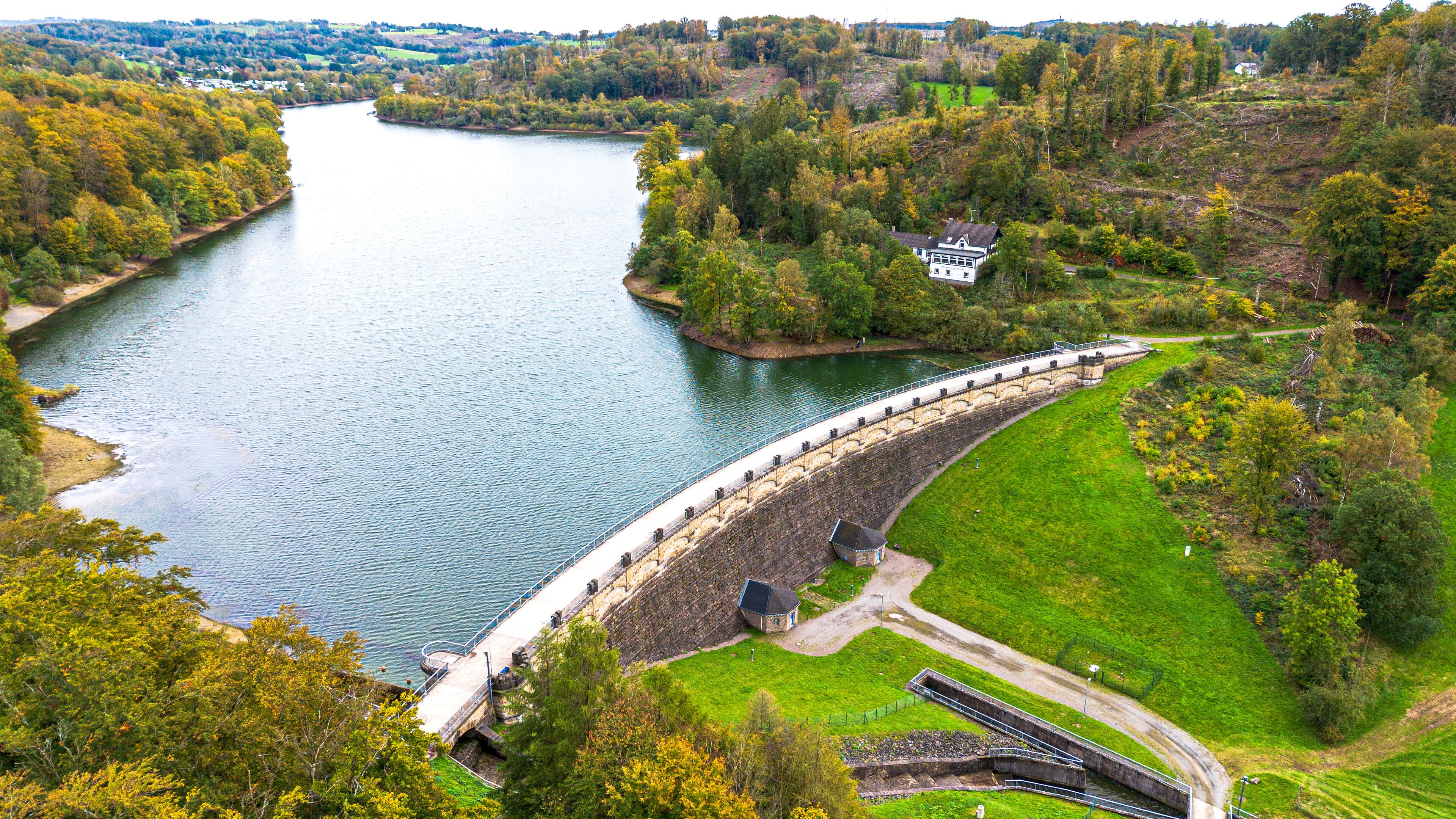 A dam with a bridge, a river, and surrounding greenery.