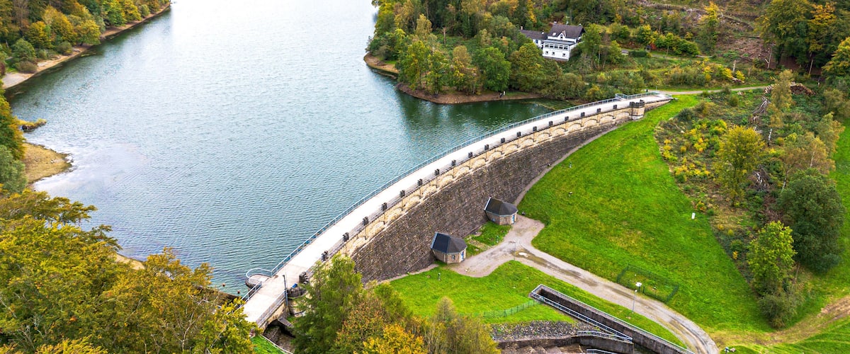 A dam with a bridge, a river, and surrounding greenery.