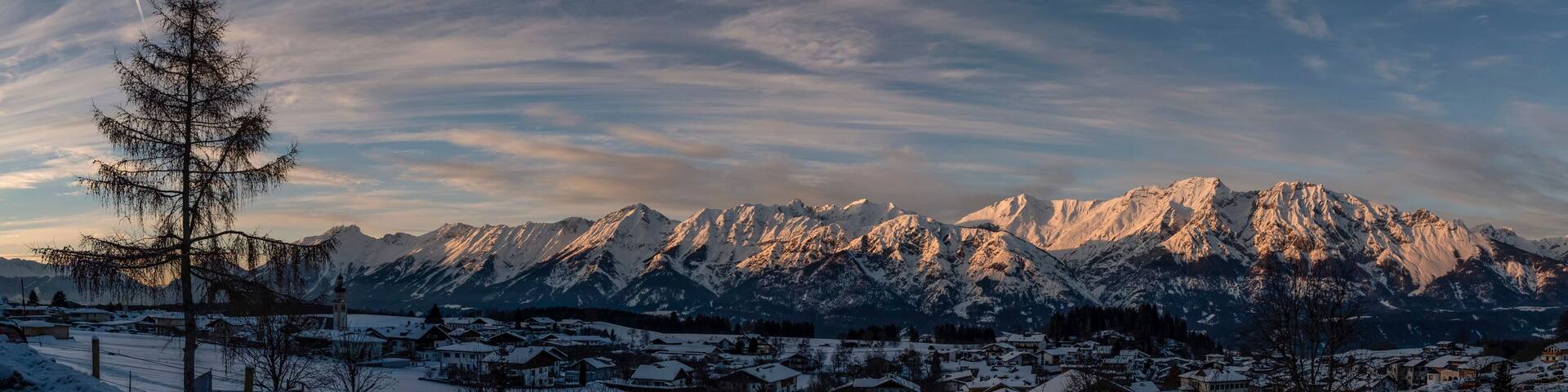 Panoramic view on Austrian village Tulfes near Innsbruck and Heiliger Apostel Thomas church in winter day at sunset.