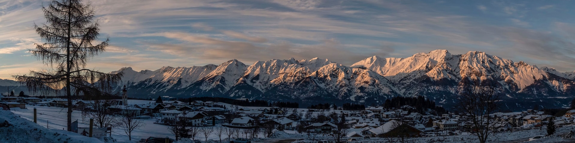 Panoramic view on Austrian village Tulfes near Innsbruck and Heiliger Apostel Thomas church in winter day at sunset.