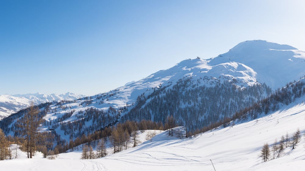 Ein verschneites Gebirge mit blauem Himmel.