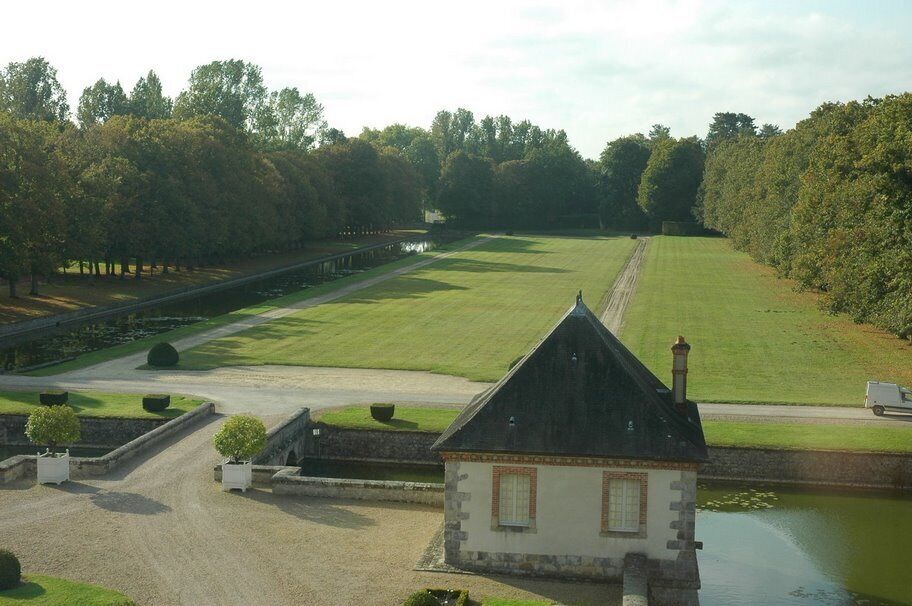 A landscaped estate with a pond, a small building, and a pathway.