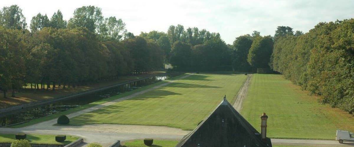 A landscaped estate with a pond, a small building, and a pathway.