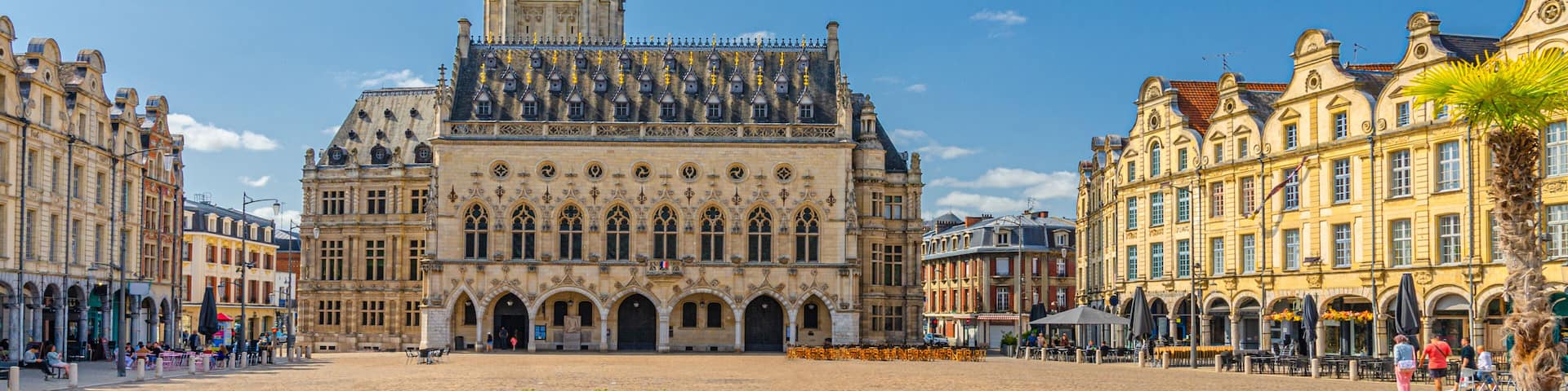 A historic building with a tall tower, a large open square, and surrounding classic architecture.