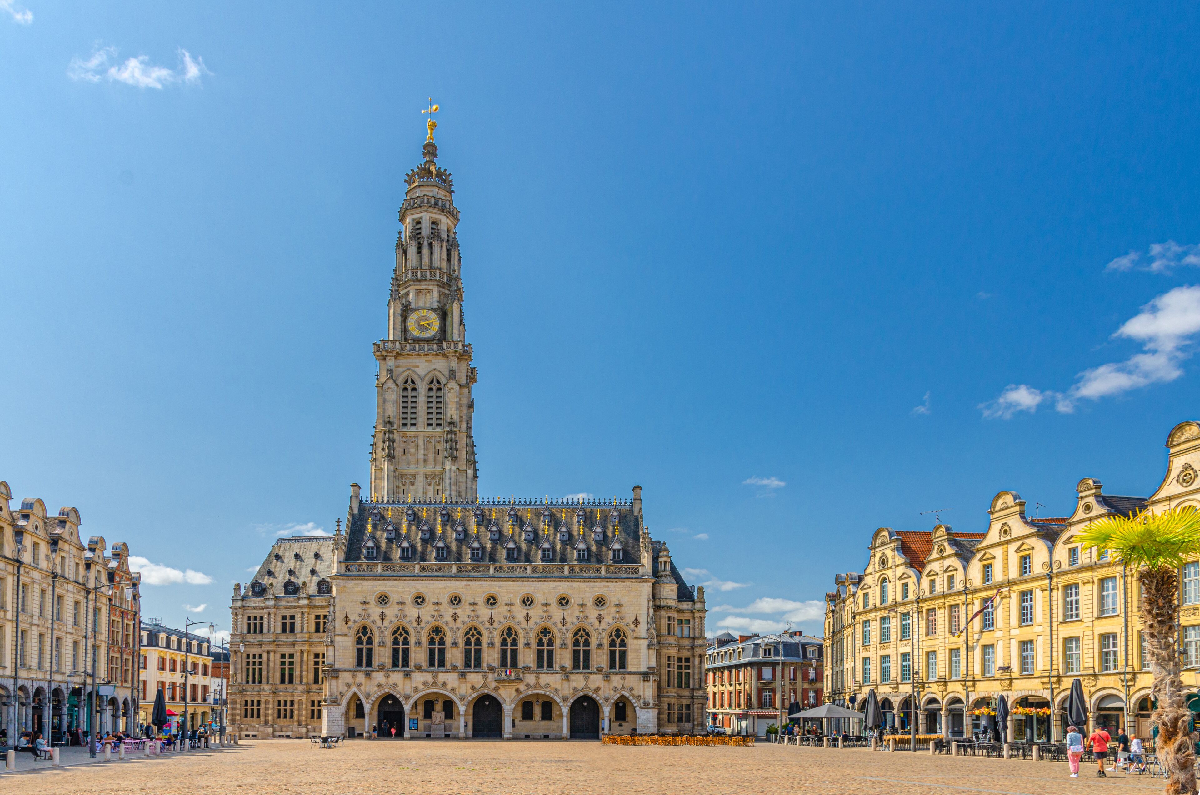 A historic building with a tall tower, a large open square, and surrounding classic architecture.