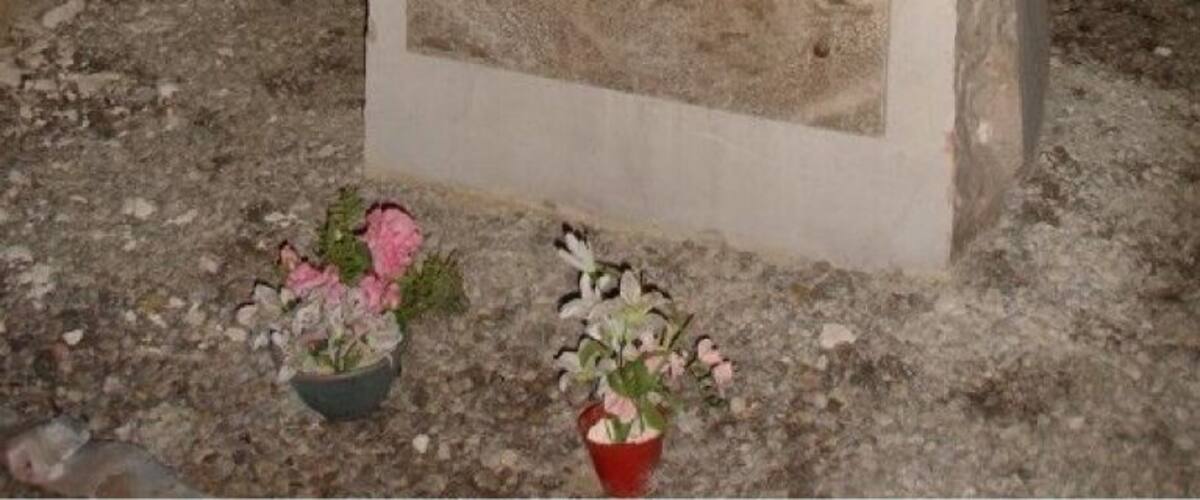 A memorial plaque with inscriptions in French, surrounded by flowers.
