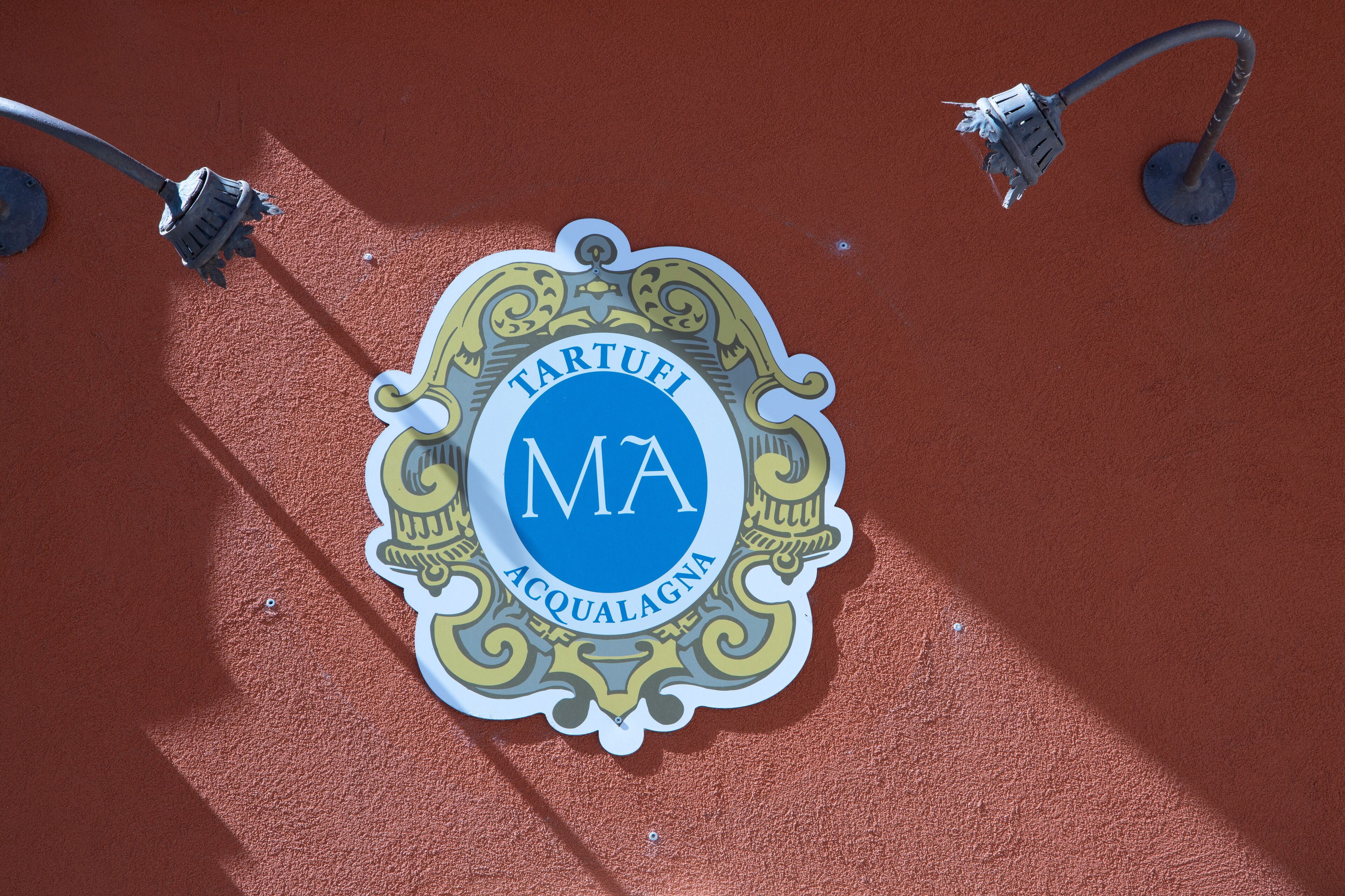 A sign with the text "TARTUFI ACQUAGNA" on a red wall.