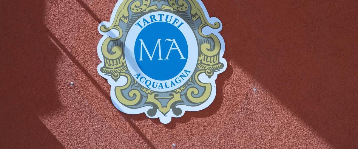 A sign with the text "TARTUFI ACQUAGNA" on a red wall.