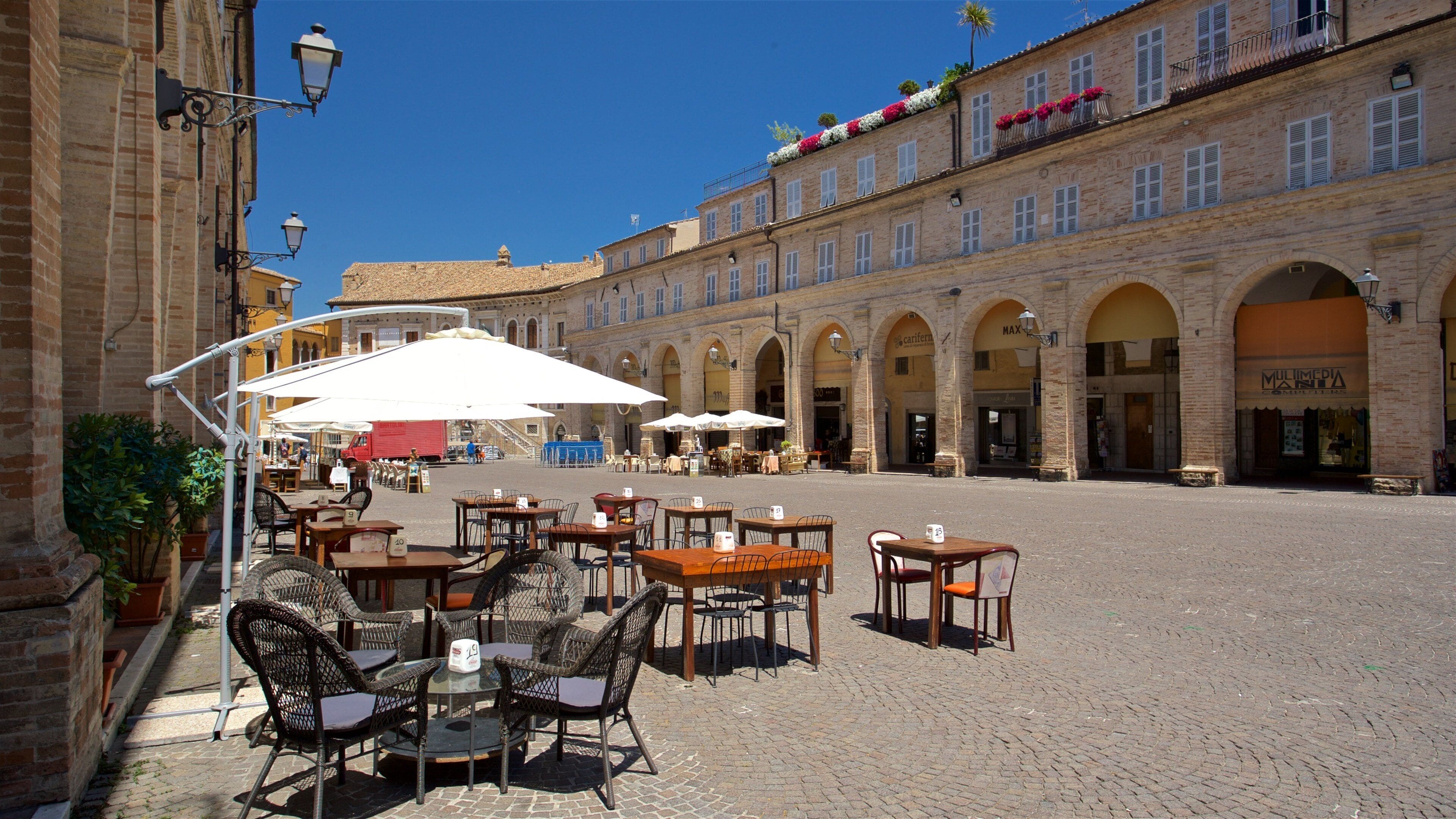 A cobblestone square with outdoor seating and brick buildings.