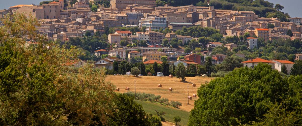 A historic town with a prominent church and tower, surrounded by lush greenery and rolling hills.
